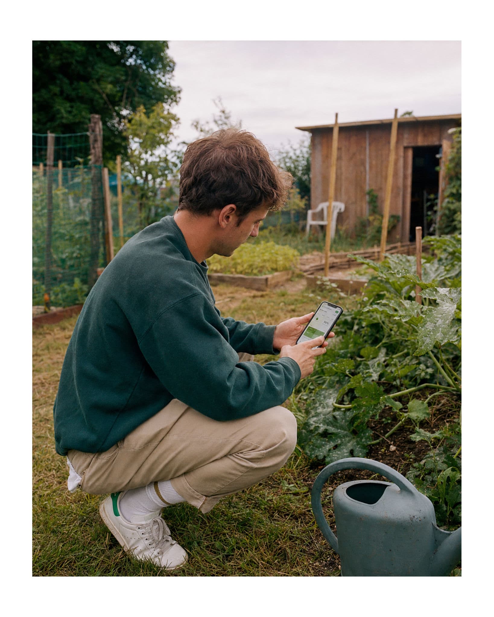 Jardinier dans son potager vérifiant le plan d'irrigation sur l'application mobile Irrigate