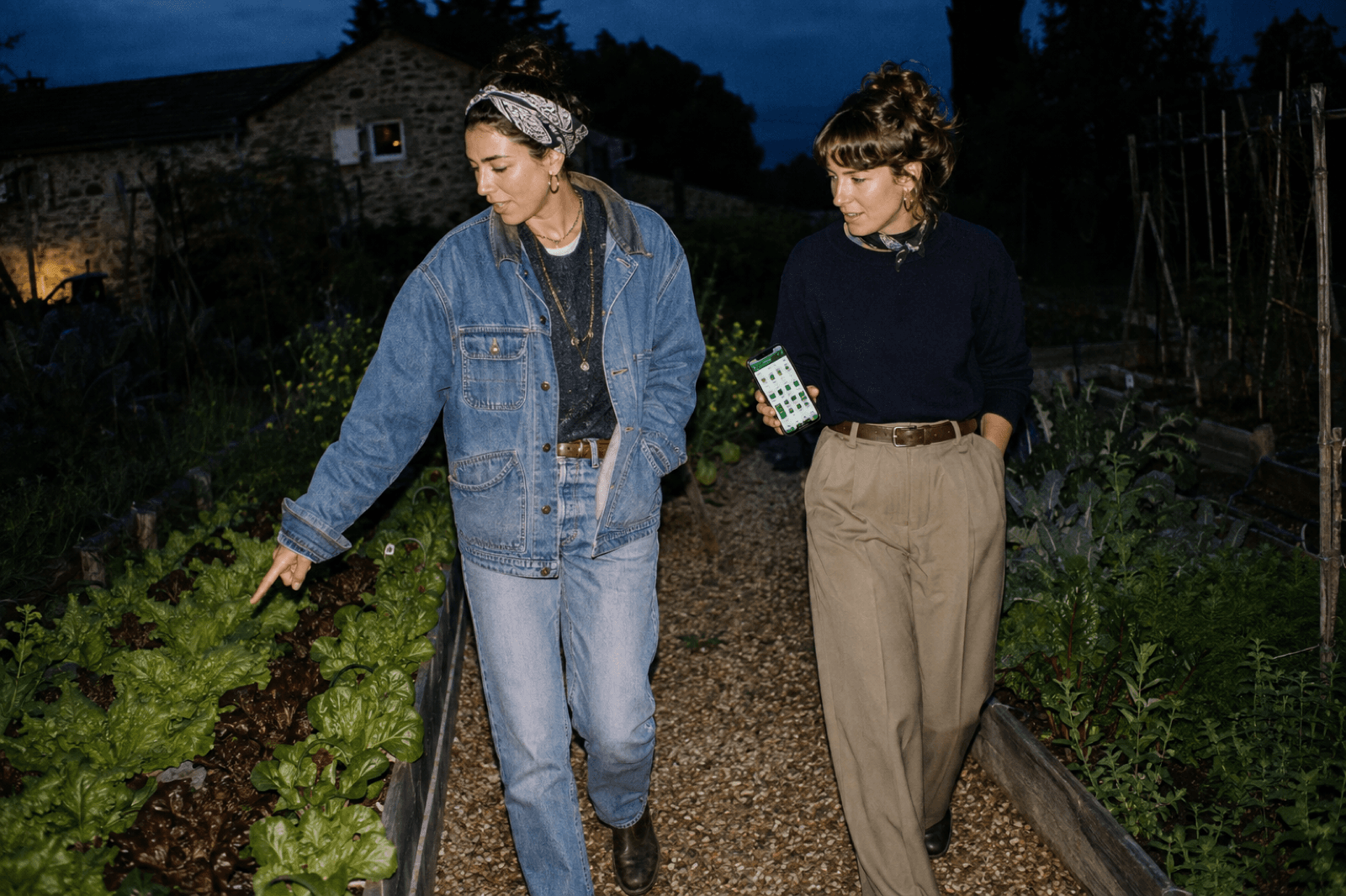 Deux jardinières parcourant les planches de légumes le soir avec l'app